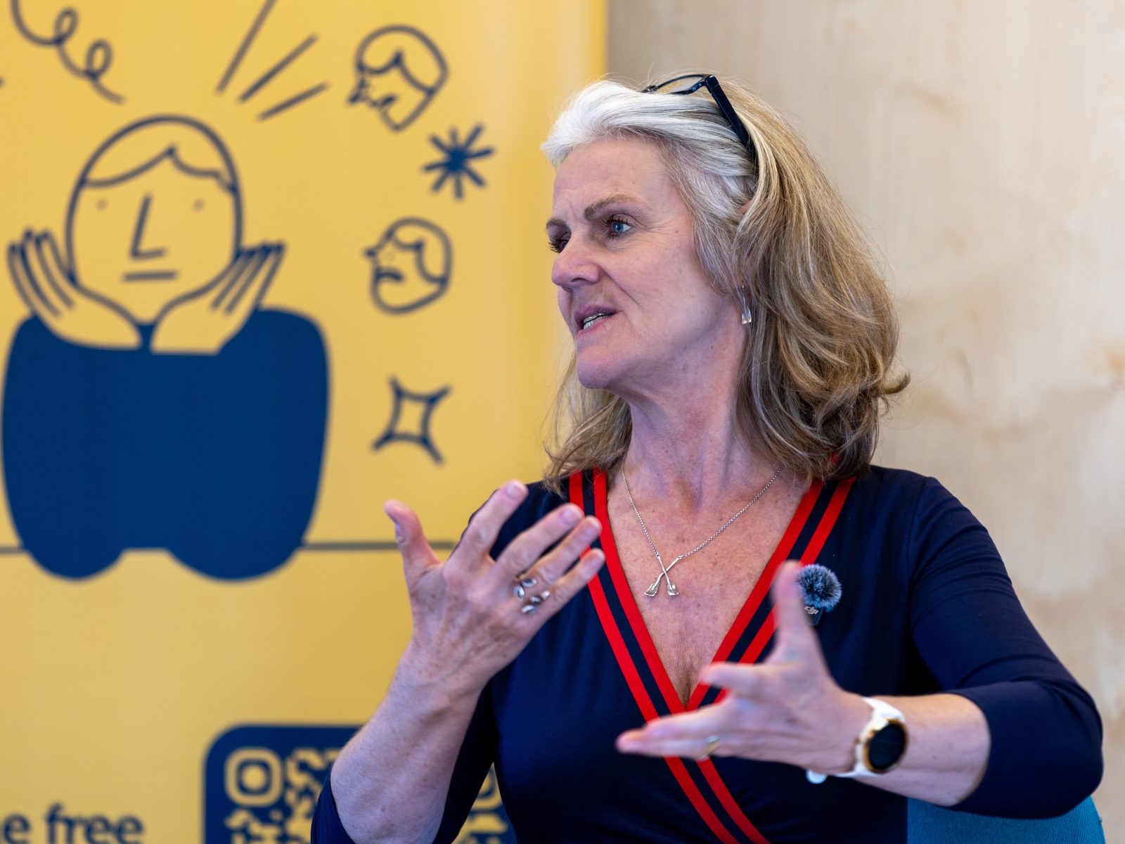 Jill teaching a group, mid-flow in front of a bright yellow banner